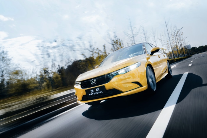 Yellow Honda Integra driving on a road