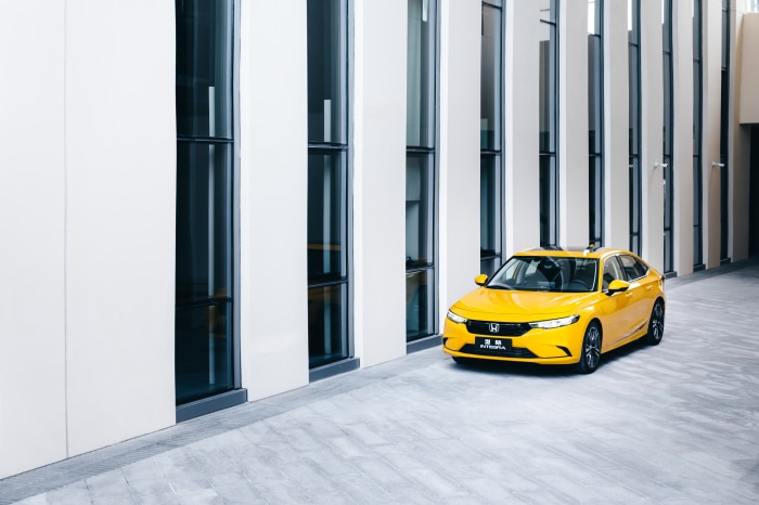 Yellow Honda Integra parked by modern building