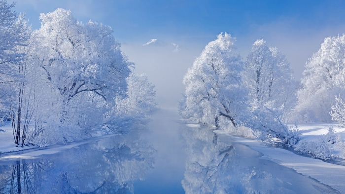 Winter river with snow-covered trees and mountains