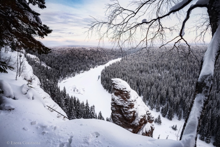 Winter forest landscape with frozen river and rock formations