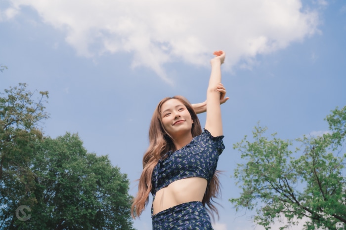 Asian woman in floral crop top stretching outdoors