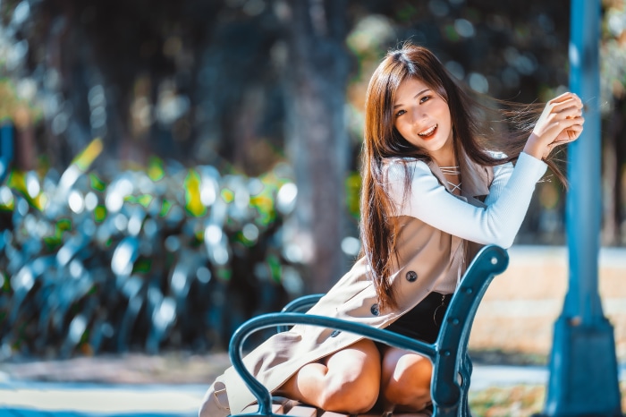 Asian woman sitting on a park bench