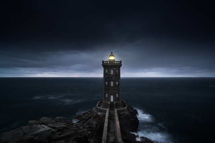 Lighthouse on a rocky outcrop at dusk
