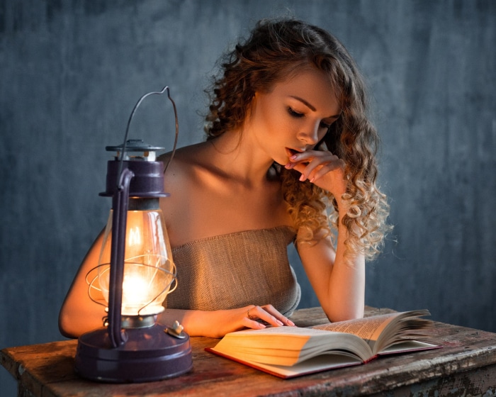 Woman reading by lantern light