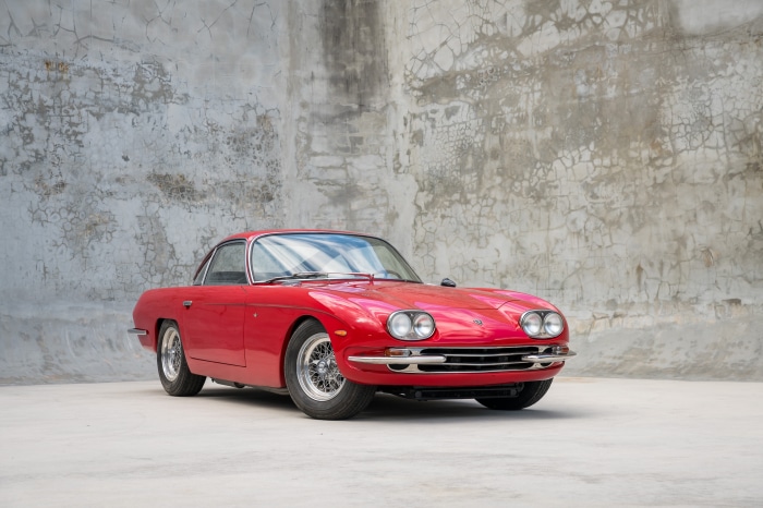Red Lamborghini 400 GT parked in front of a concrete wall
