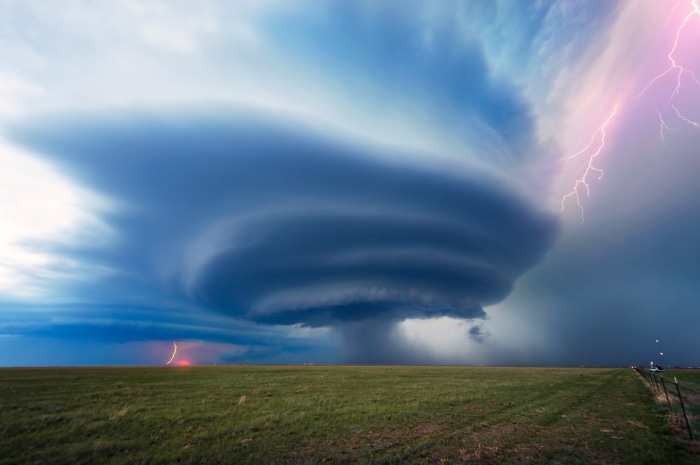 Supercell thunderstorm with lightning over a grassy plain