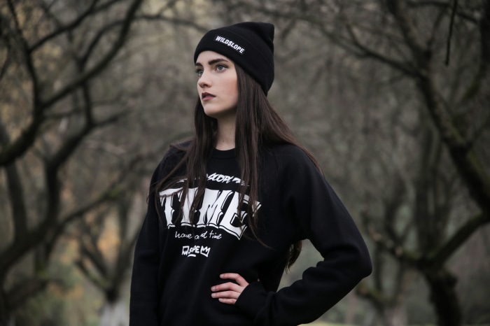 Model with black hair wearing a black beanie and sweatshirt