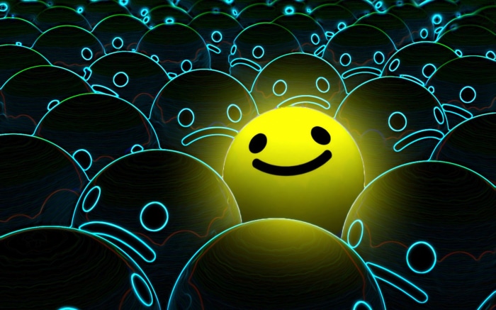 A single yellow smiley face among many dark, sad faces