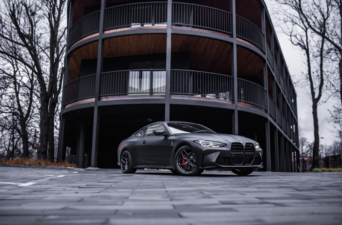 Matte black BMW M4 coupe parked in front of a modern building