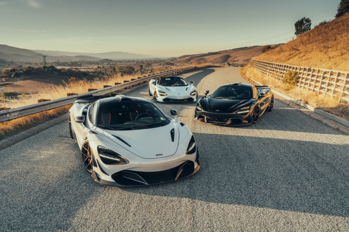Three McLaren supercars on a winding road
