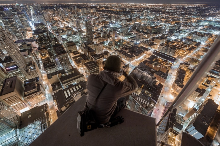 Person on a skyscraper roof overlooking city lights