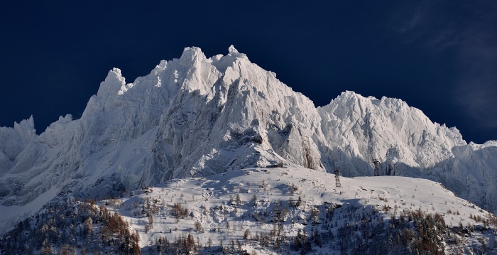Snow-covered Aiguilles de Chamonix mountains under a dark blue sky