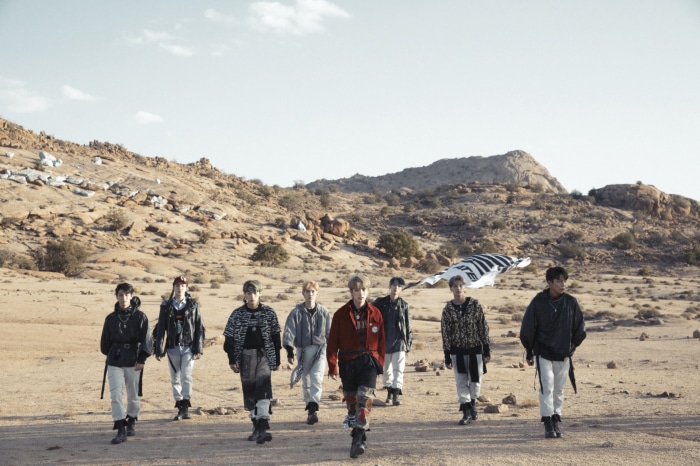 ATEEZ members walking in a desert landscape