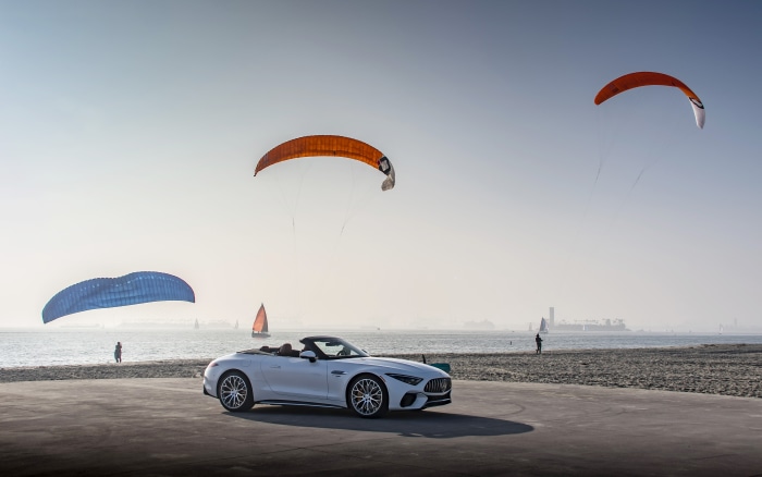White Mercedes-AMG SL Cabriolet on beach with kite surfers