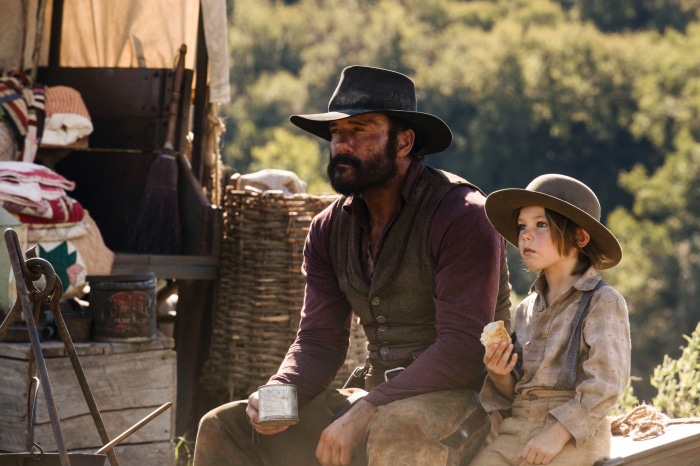 Man and child in western attire near a wagon