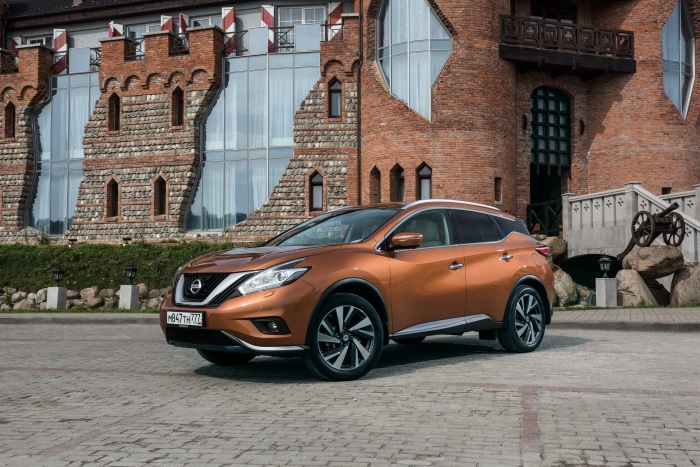 Orange Nissan Murano SUV in front of castle-like building