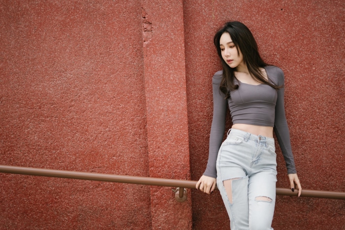 Asian Woman with Black Hair Wearing Gray Crop Top and Ripped Jeans