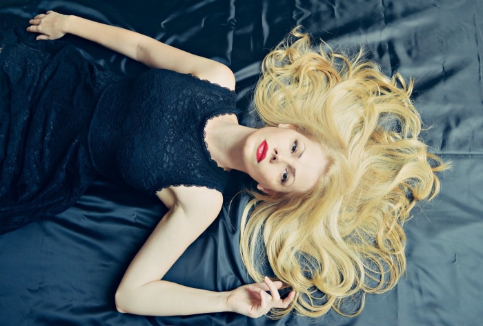 Woman in black dress lying on satin sheets