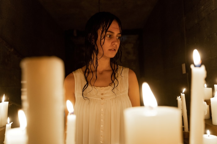 Woman in white dress surrounded by candles