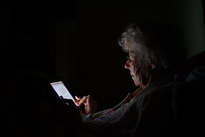 Elderly woman reading on a tablet in the dark