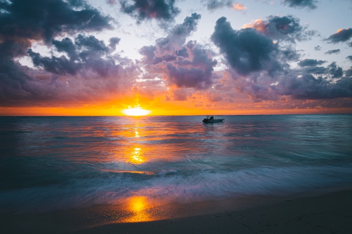 Sunrise over the ocean with a small boat