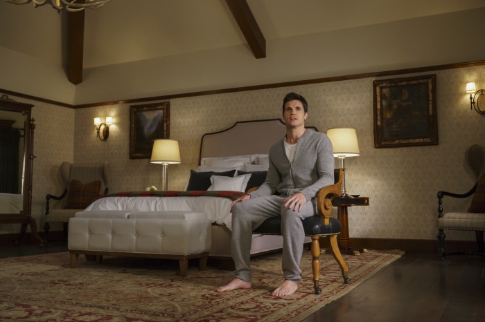 Robbie Amell in a bedroom
