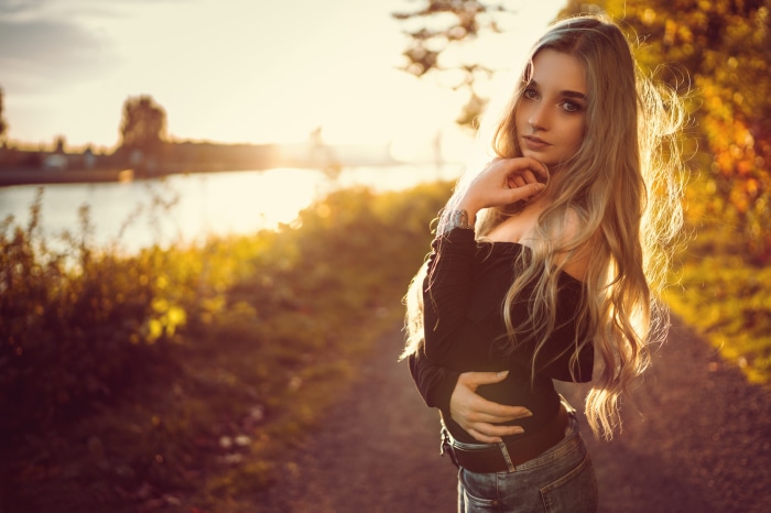 Model posing by a river at sunset