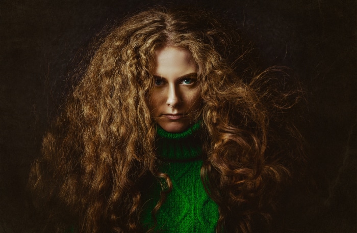 Woman with curly red hair wearing a green turtleneck
