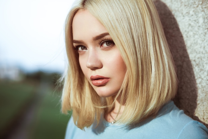 Young woman with blonde hair leaning against a wall