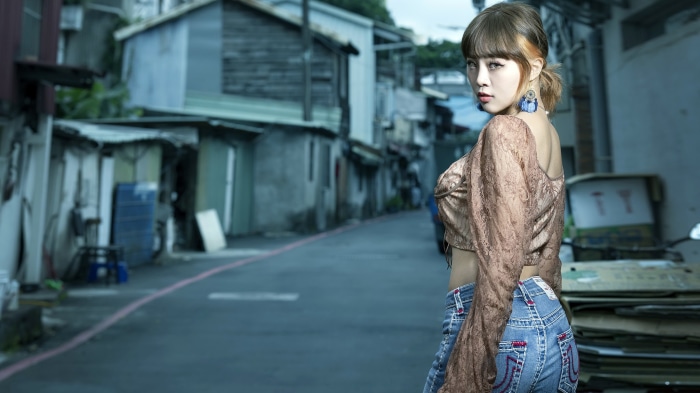 Asian woman in jeans and lace top in alley