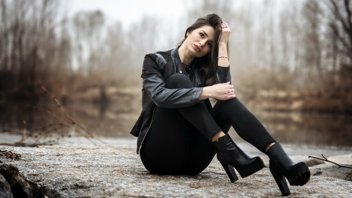 Woman in black jacket and pants sitting on rocks