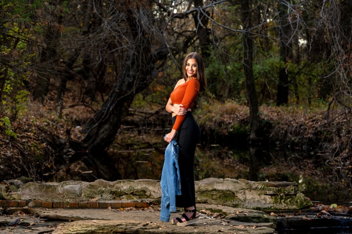 Model posing in a forest with a denim jacket