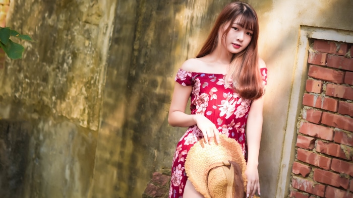 Asian woman in floral dress holding a hat