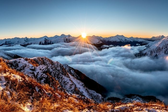 Sunrise over a sea of clouds in snowy mountains