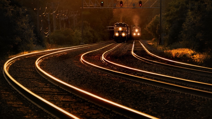Two trains on railroad tracks at sunset