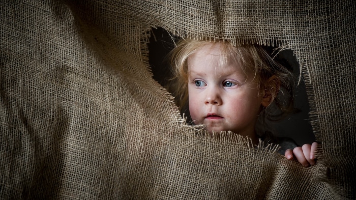 Child peeking through burlap