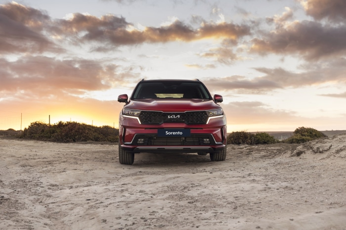 Red Kia Sorento SUV on a beach at sunset