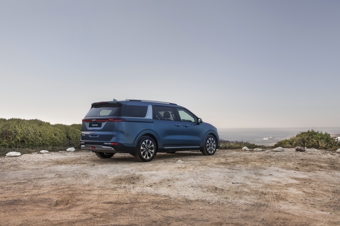 Blue Kia Carnival parked near the ocean