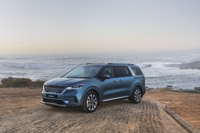 Blue Kia Carnival parked by the ocean