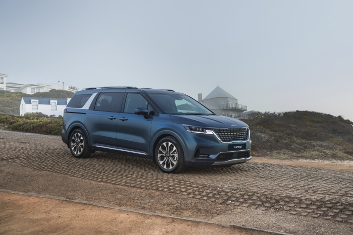 Blue Kia Carnival parked on a coastal road