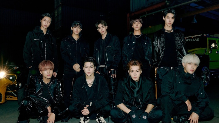 NCT members in black outfits with a car