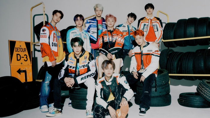 NCT members in racing outfits with tires