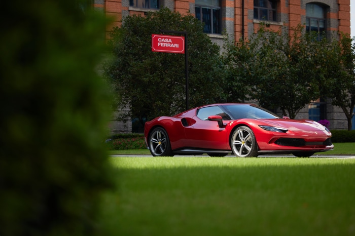 Red Ferrari 296 GTB parked near Casa Ferrari sign