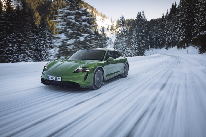 Green Porsche Taycan Turbo S driving on a snowy road