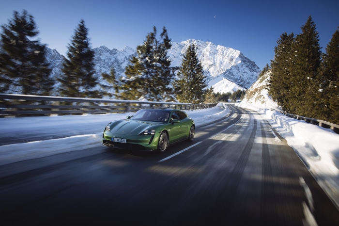 Green Porsche Taycan Turbo S driving on a snowy mountain road