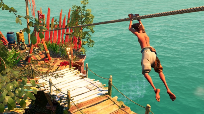 Boy ziplining over turquoise water near wooden structures
