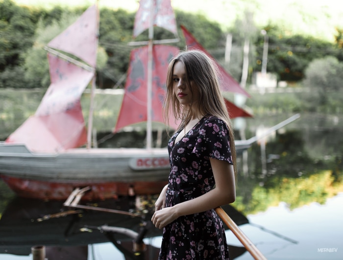 Young woman in a floral dress by a boat