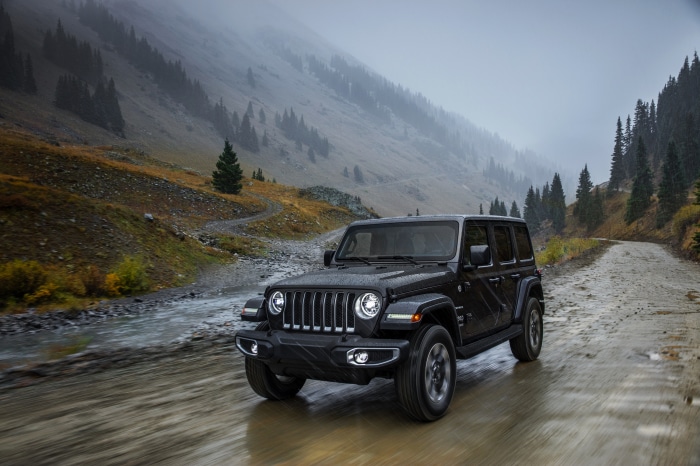 Black Jeep Wrangler driving on a wet mountain road