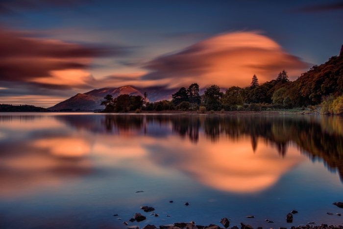 Lake reflection at dawn with mountains and clouds