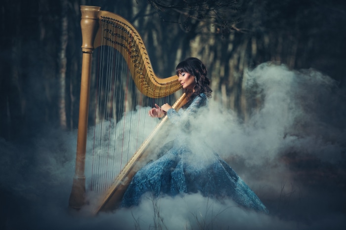 Woman playing harp in foggy forest